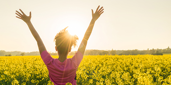 Consultations - Mixed race African American girl female young woman athlete runner teenager in golden sunset or sunrise arms raised celebrating in field of yellow flowers